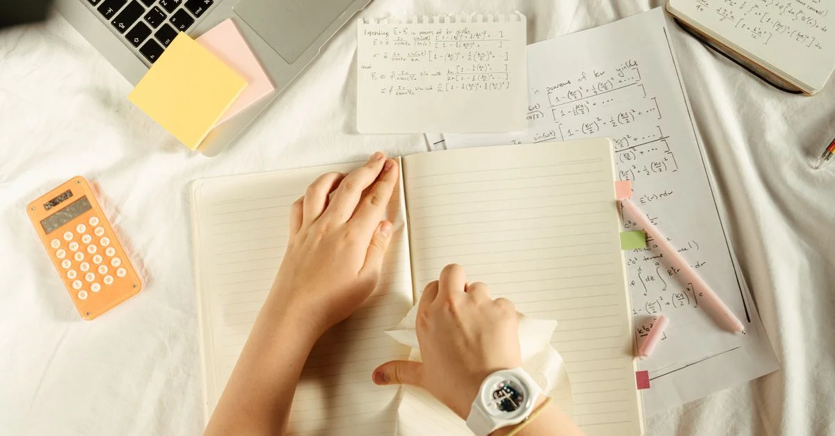 Vue aérienne des fournitures d'étude avec un ordinateur portable, une calculatrice et un carnet sur un bureau.
