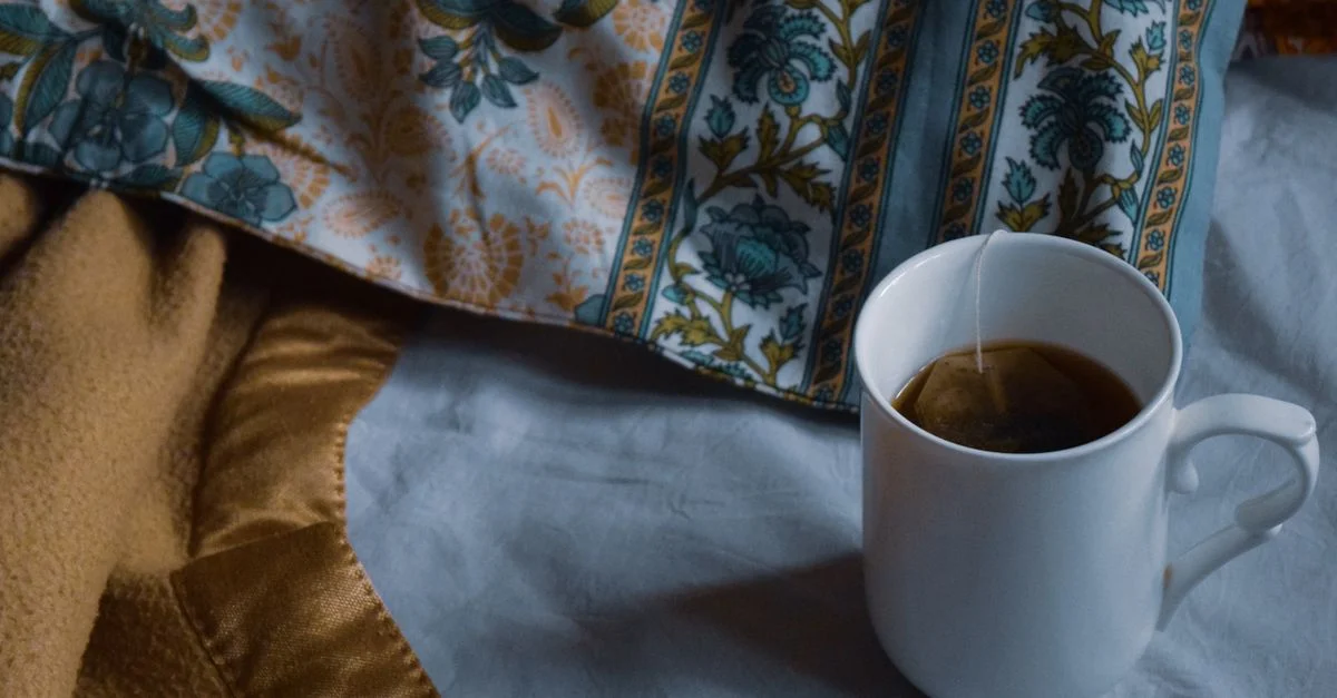 Une tasse de thé fumante sur une douce couverture de lit crée une ambiance chaleureuse et accueillante.