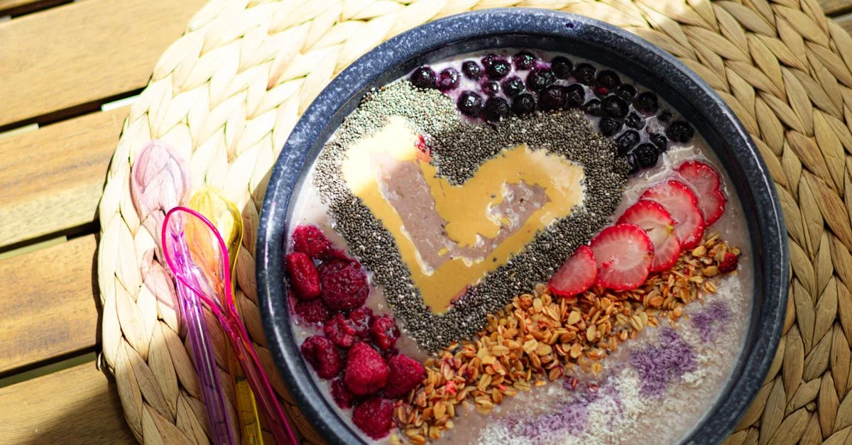 Bol de smoothie coloré avec des baies, des graines de chia et un cœur de beurre de cacahuète pour un petit-déjeuner sain.