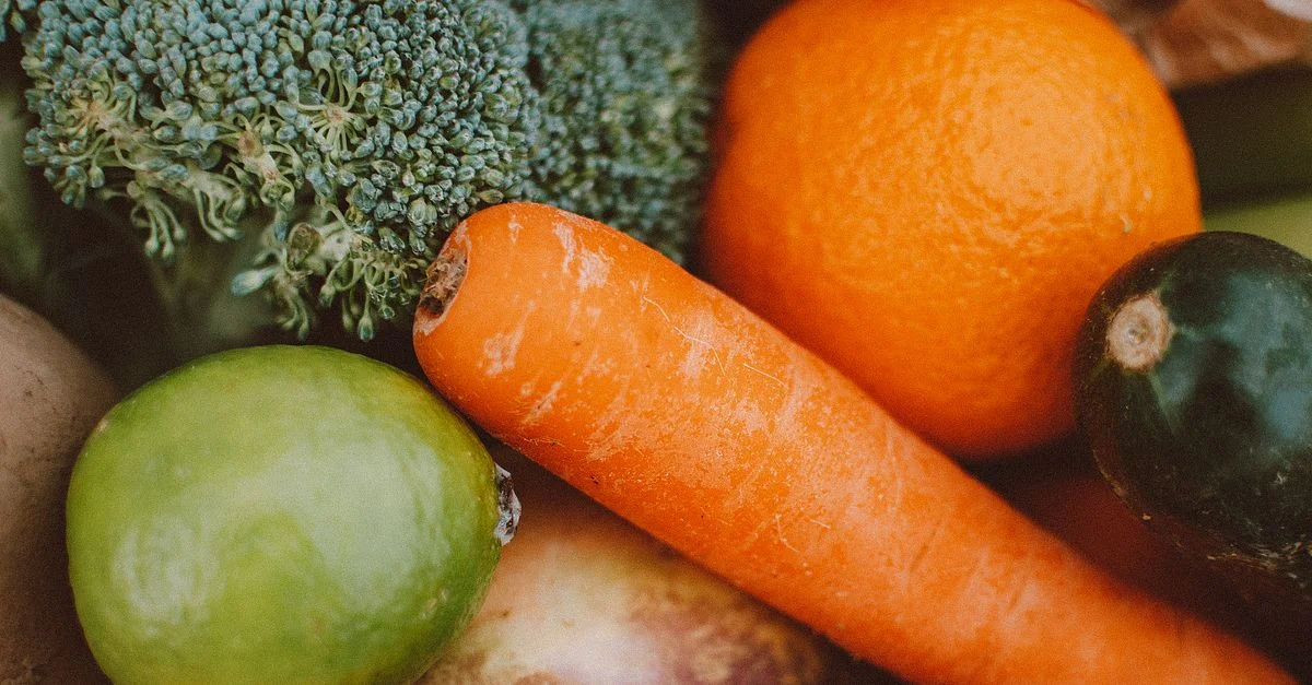Une collection vibrante de légumes et de fruits frais comprenant des carottes, du brocoli et des oranges.