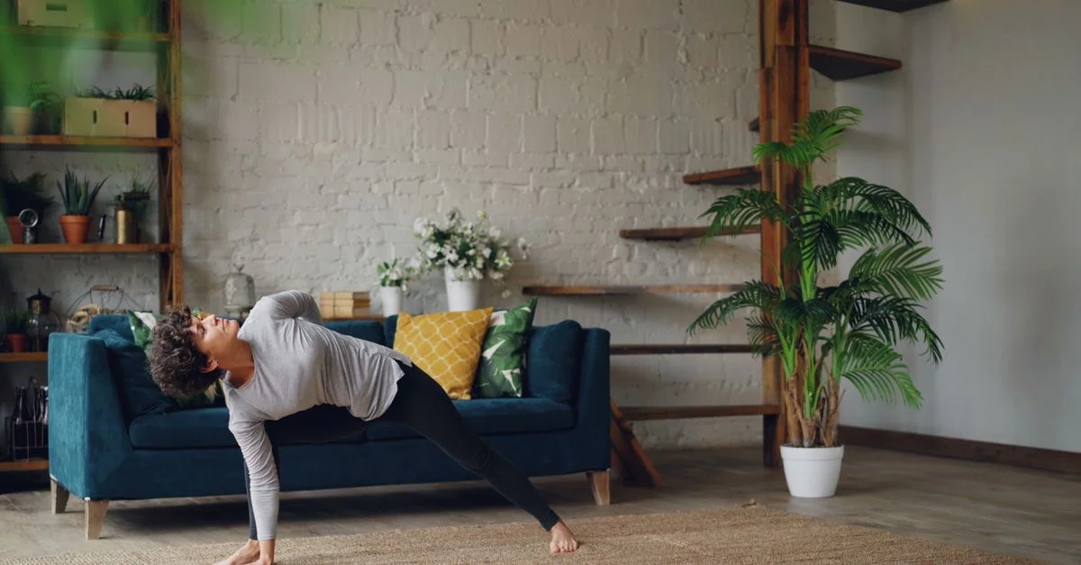 Femme pratiquant le yoga en intérieur, dans un décor moderne baigné de lumière naturelle.