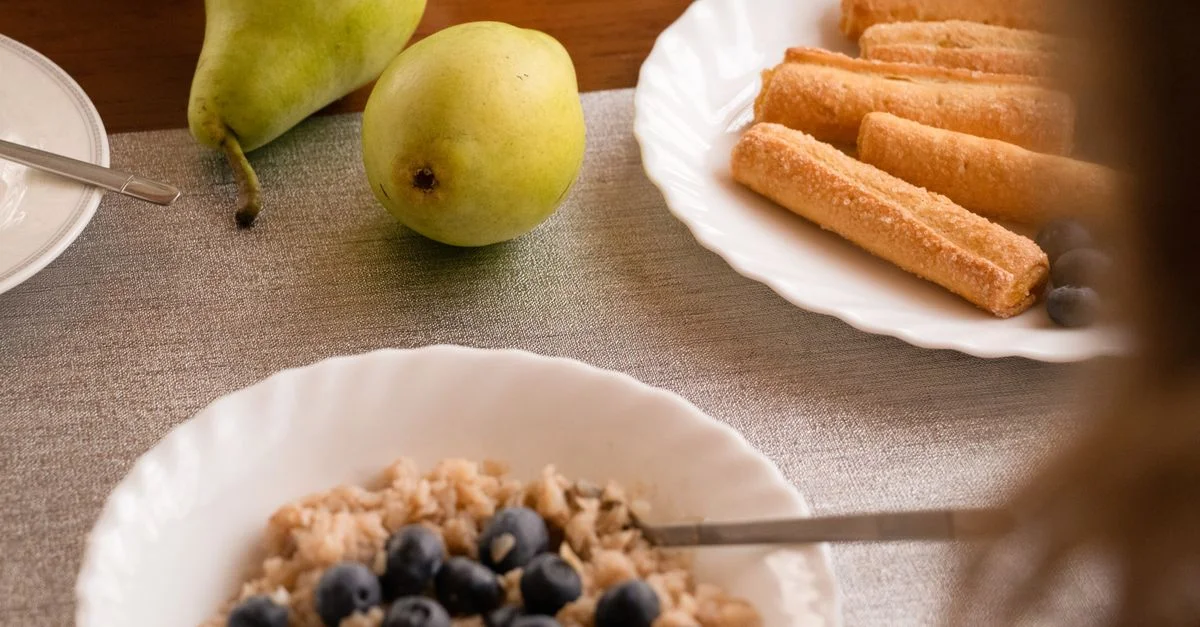 Une scène de petit-déjeuner chaleureuse avec du gruau aux myrtilles, des poires et des viennoiseries.