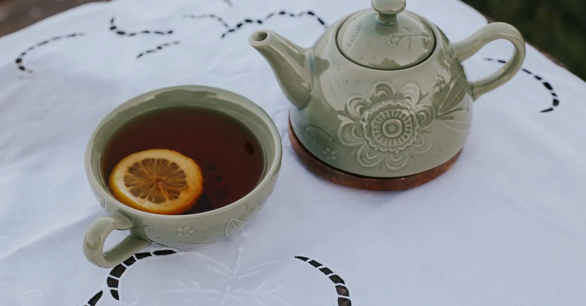Charmante théière verte et tasse avec une tranche de citron sur un linge décoratif blanc en plein air.