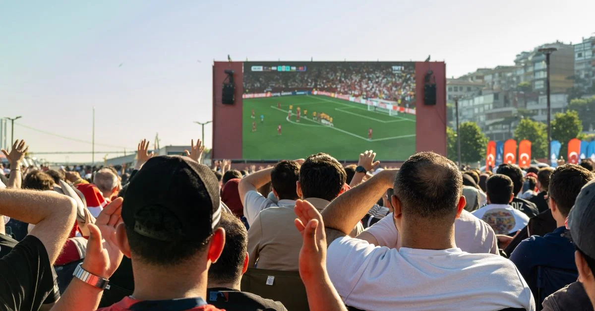 Foule regardant un match de football sur un grand écran en extérieur à Istanbul, Türkiye.