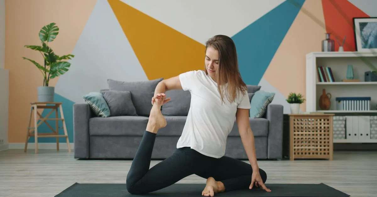 Une femme pratique le yoga sur un tapis dans un salon moderne et coloré.