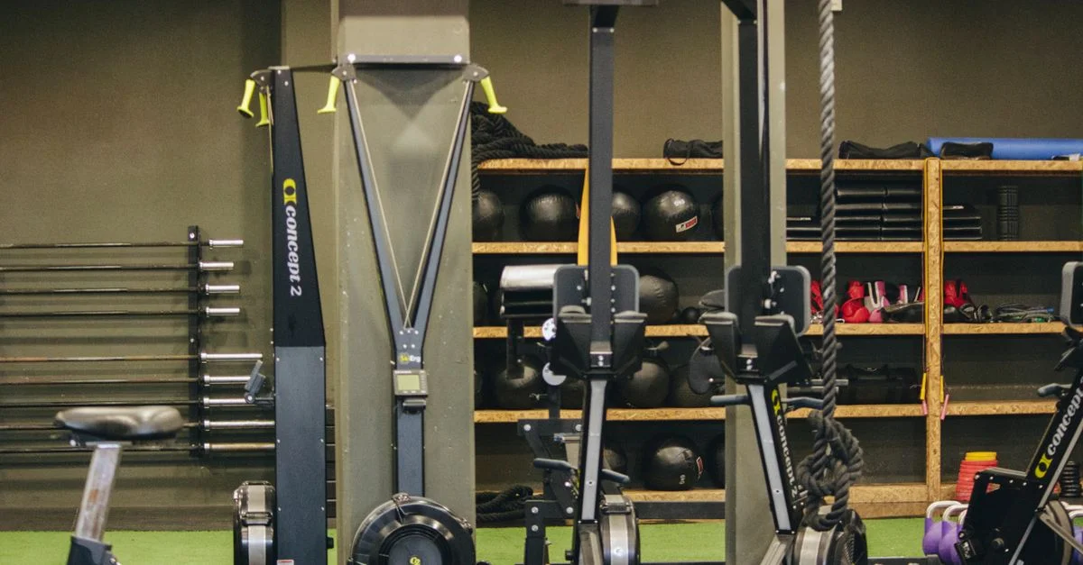 Salle de sport moderne avec équipement d'exercice comprenant des machines à ramer et à skier, des poids et des cordes.
