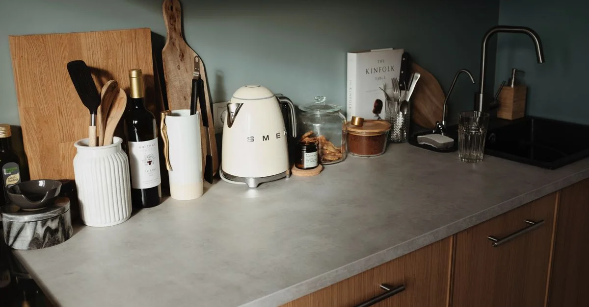 Un plan de travail de cuisine moderne avec une bouilloire Smeg, du vin, des ustensiles et des éléments décoratifs en bois.