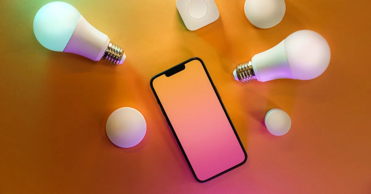 Vue de dessus d'un smartphone avec des ampoules intelligentes sur un fond jaune vif, illustrant la technologie moderne.