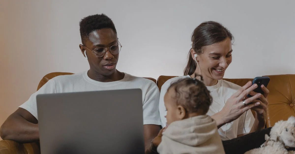 Une famille profitant d'un moment de qualité ensemble en utilisant des appareils technologiques comme des ordinateurs portables et des smartphones.
