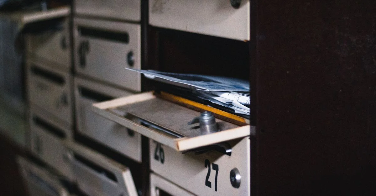 Gros plan sur une boîte aux lettres ouverte dans un immeuble résidentiel avec du courrier visible, mettant en valeur la mise au point sélective.