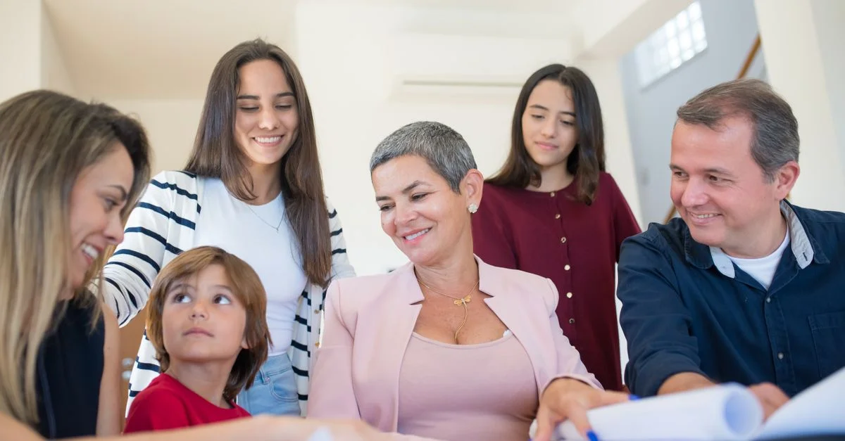 Une famille se réunissant autour d'une table, discutant de documents immobiliers à l'intérieur avec un agent immobilier.