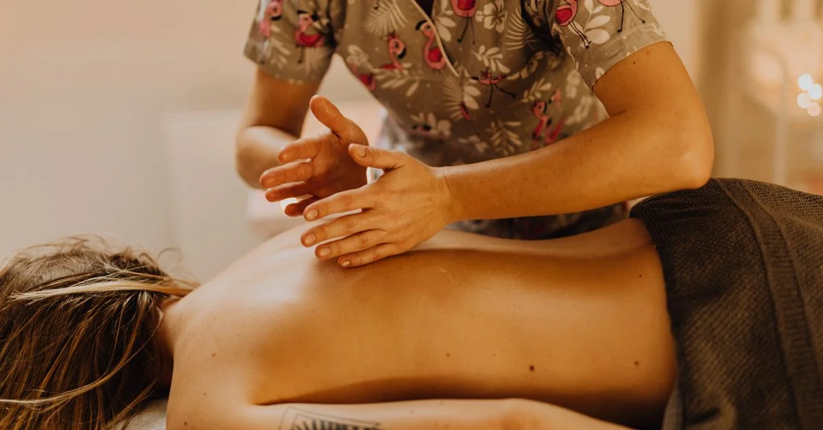 Une séance de massage relaxante avec un thérapeute s'occupant d'une femme tatouée dans un spa.