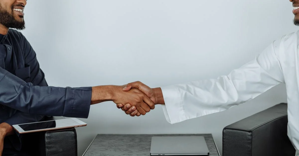 Deux hommes d'affaires se serrent la main en signe d'accord lors d'une réunion, symbolisant le partenariat.
