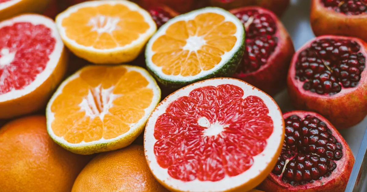 Gros plan vibrant de fruits citriques et de grenades tranchés mettant en valeur la fraîcheur et la variété.