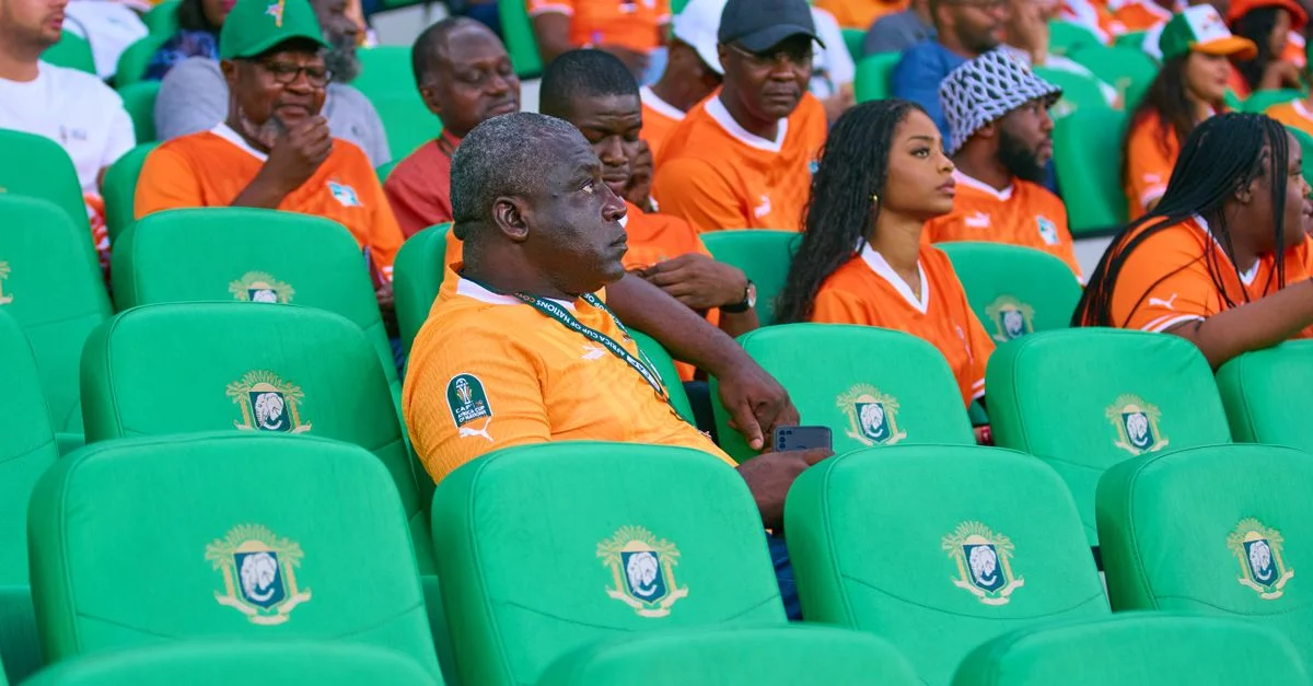 Spectateurs excités en maillots orange remplissant les sièges du stade, créant une scène vibrante.