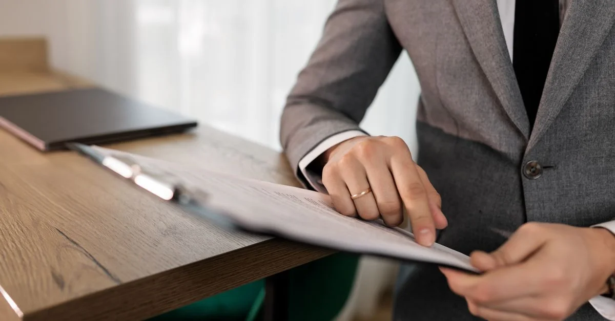 Homme d'affaires professionnel en costume examinant des documents sur un clipboard à son bureau.