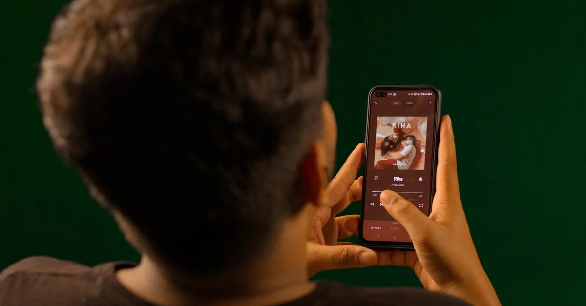Une personne utilisant un smartphone pour diffuser de la musique depuis une application de service de streaming à l'intérieur.