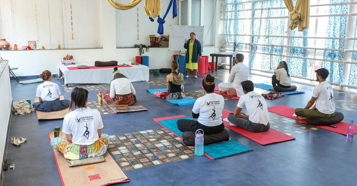 Groupe d'adultes participant à un cours de yoga dans un studio spacieux et moderne avec un instructeur.