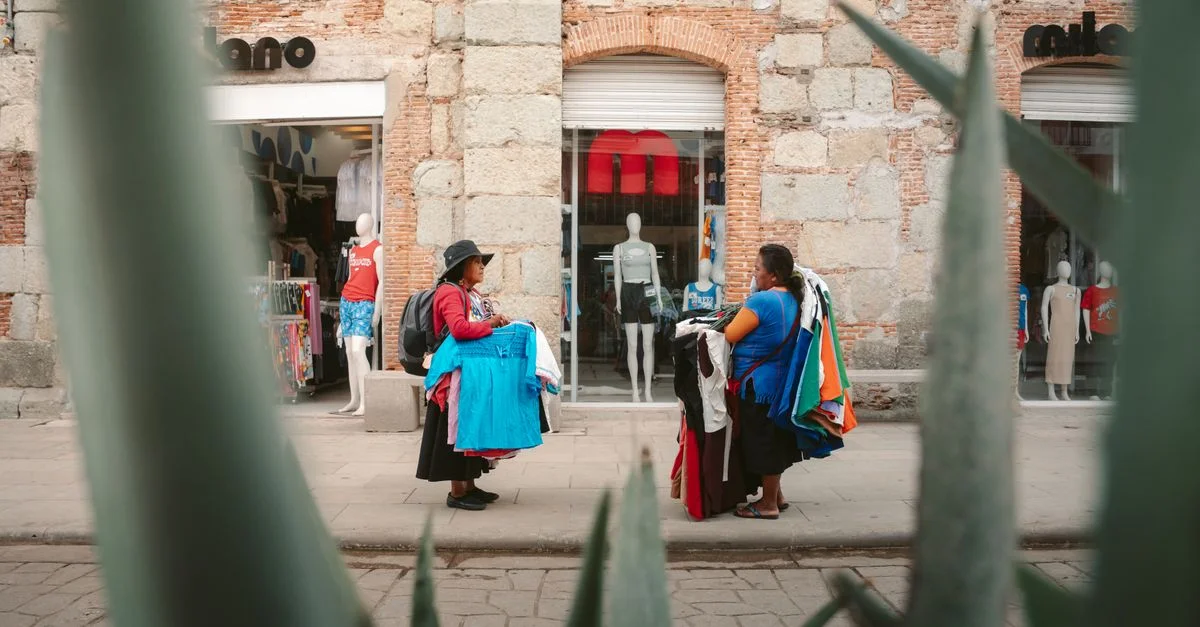 Scène de rue colorée à Oaxaca avec des vendeurs locaux vendant des vêtements près d'une boutique.