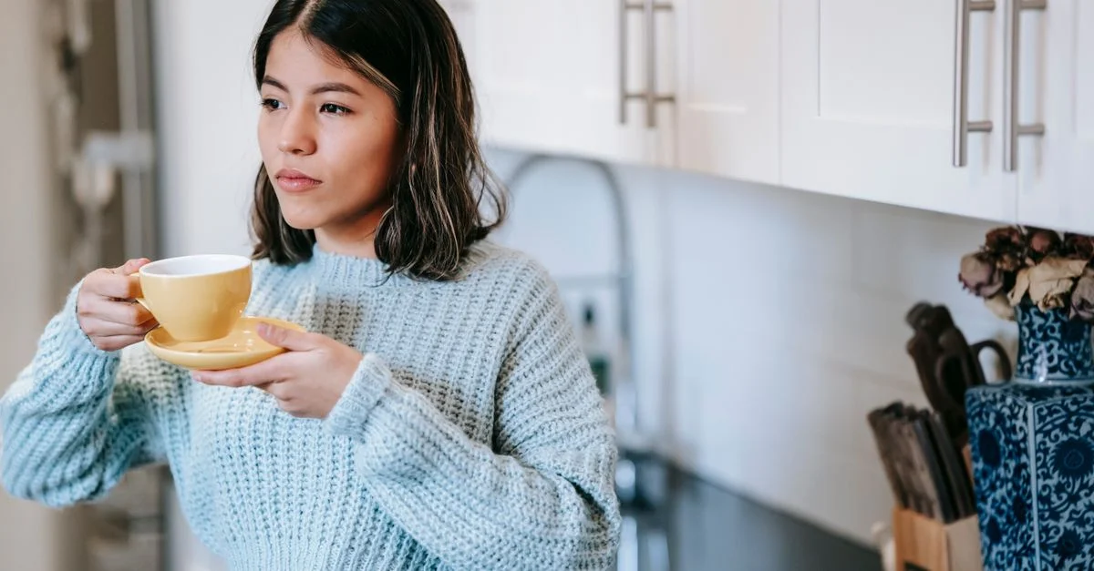 Moment matin calme avec une femme appréciant un café chaud dans une cuisine confortable.