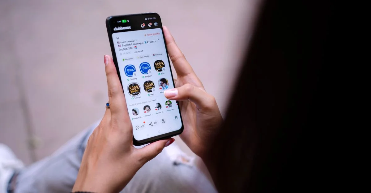 Gros plan d'une femme utilisant un smartphone avec une application de médias sociaux ouverte. Mains tenant l'appareil.