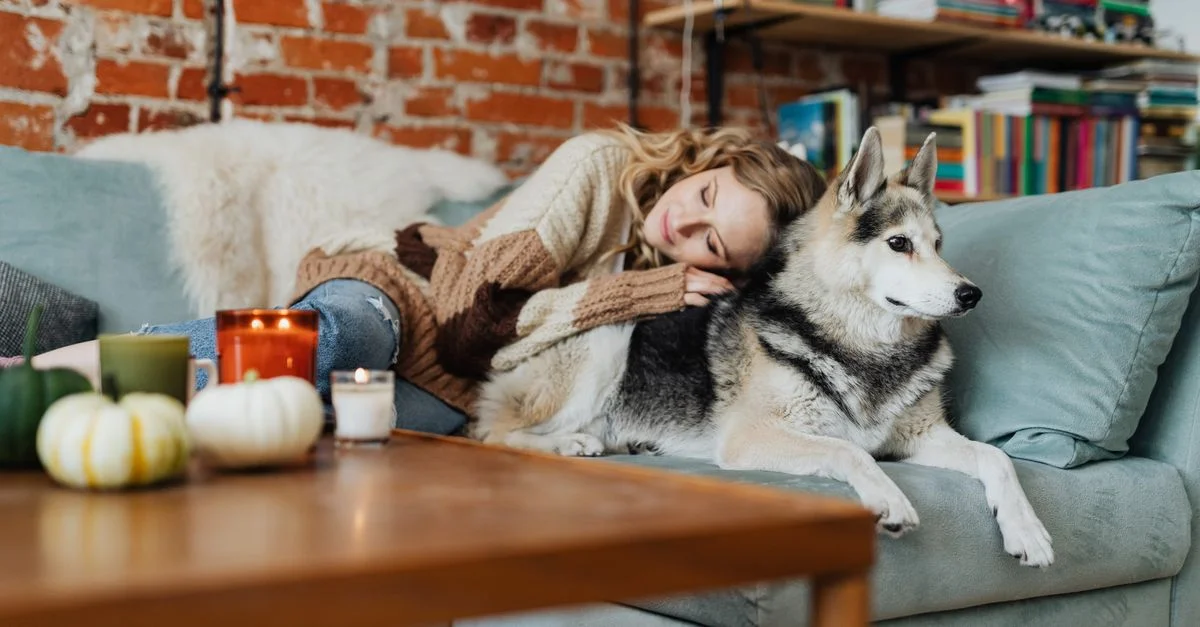 Femme se reposant avec son chien dans un cadre de salon confortable, évoquant chaleur et confort.