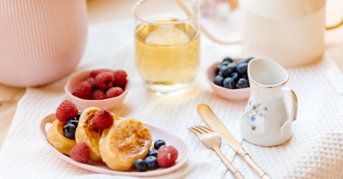 Une ambiance de petit-déjeuner douillette avec des pancakes aux baies et du thé, parfait pour une douceur matinale.